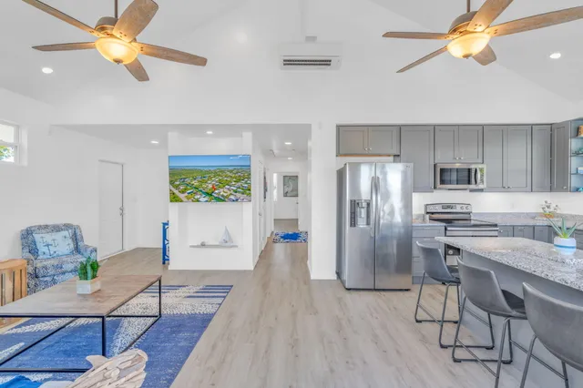 a kitchen with stainless steel appliances granite countertop a refrigerator a stove a sink a dining table and chairs with wooden floor