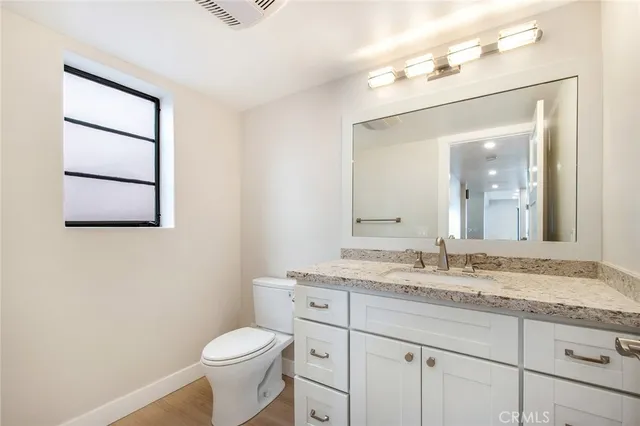 a bathroom with a granite countertop sink mirror vanity and toilet