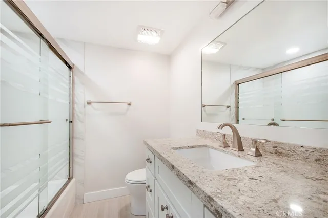a bathroom with a granite countertop sink toilet and shower
