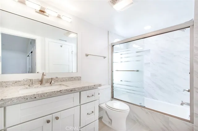 a bathroom with a granite countertop sink toilet and shower
