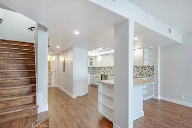 a view of a hallway with wooden floor windows and a living room