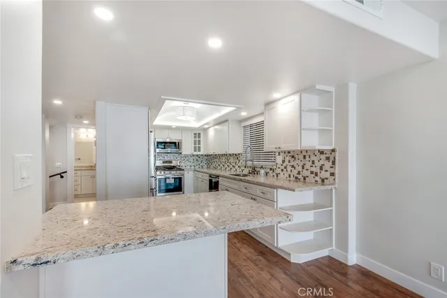 a kitchen with stainless steel appliances kitchen island granite countertop a refrigerator and a sink