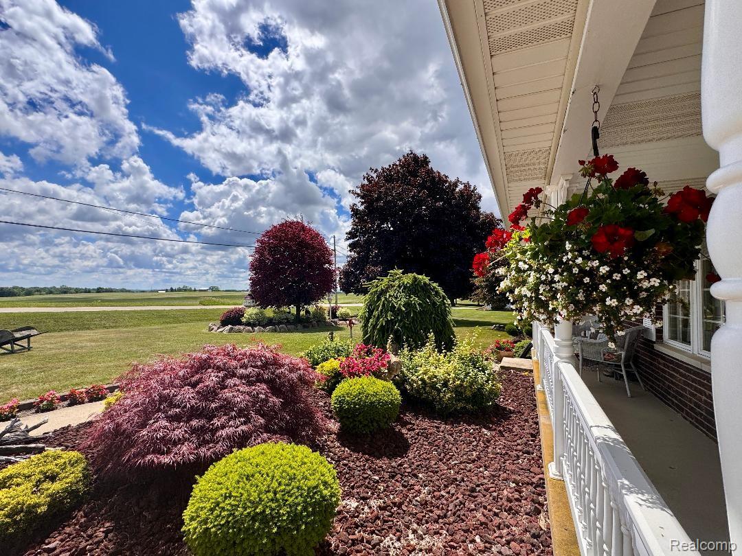 6686 South Schott Road Mayville, MI 48744 - Photo 8 of 25 Covered porch with hanging floral arrangements and white balustrade