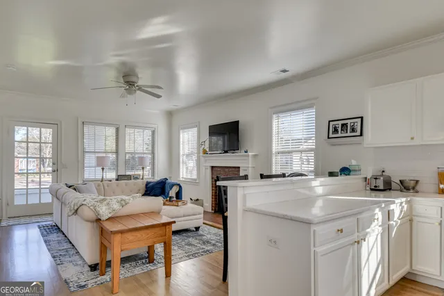 a living room with stainless steel appliances granite countertop a kitchen island hardwood floor and a sink