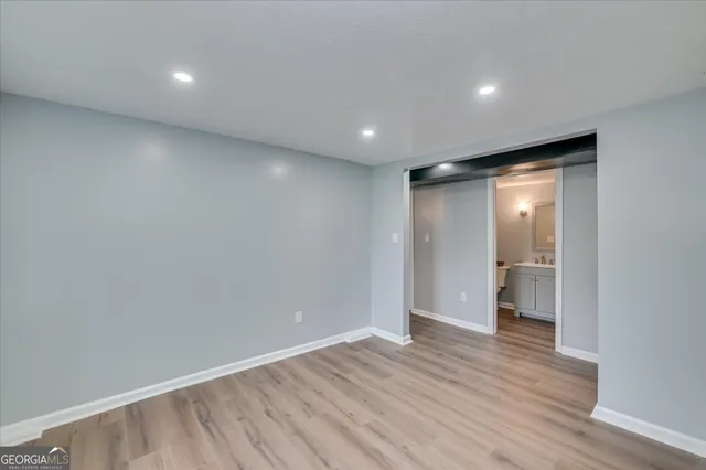 a view of an empty room with wooden floor and closet