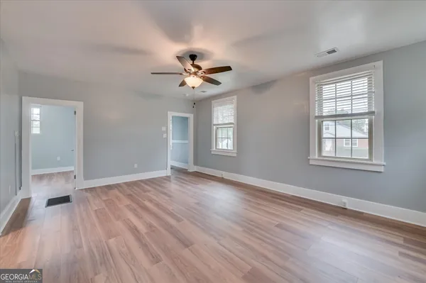 a view of an empty room with a window and wooden floor