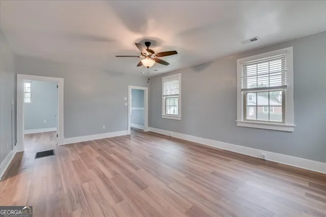 a view of an empty room with a window and wooden floor