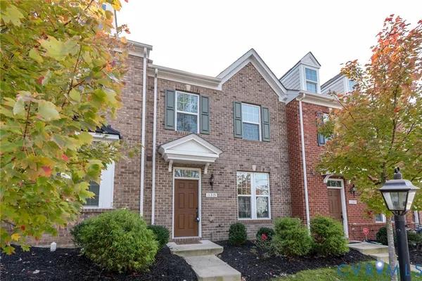 front view of a brick house with a yard and plants