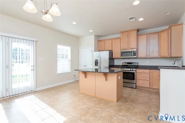 a kitchen with granite countertop a stove top oven a sink dishwasher a refrigerator and white cabinets with wooden floor