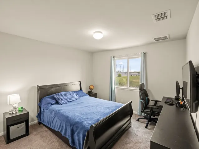 a bedroom with a bed and a flat tv screen on the dresser