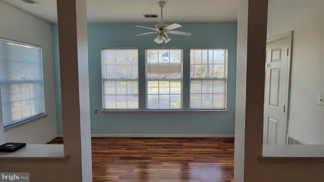 a view of an empty room with a window and wooden floor