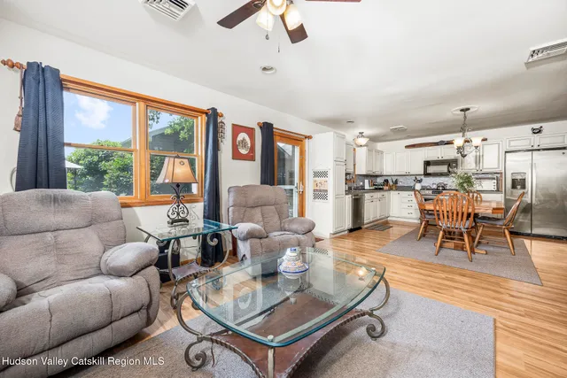 a kitchen with stainless steel appliances granite countertop a dining table chairs refrigerator and microwave