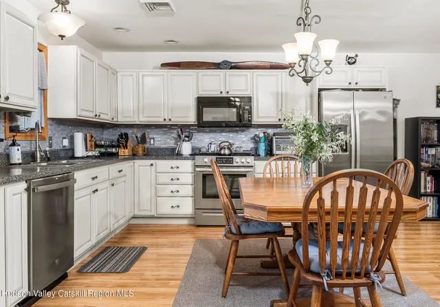 a dining room with stainless steel appliances kitchen island granite countertop a dining table chairs and a refrigerator