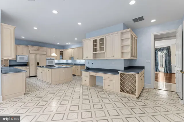 a view of a kitchen with kitchen island granite countertop a refrigerator a stove top oven a sink and a dining table with wooden floor