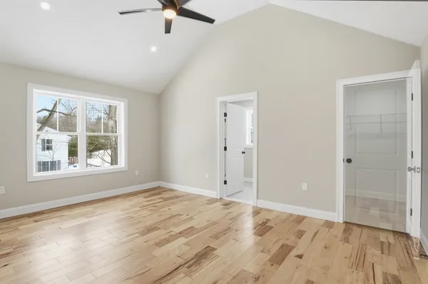 a view of empty room with wooden floor and fan