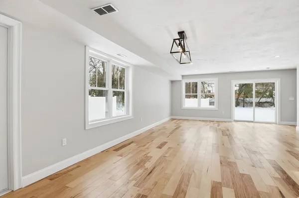 a view of an empty room with wooden floor and window