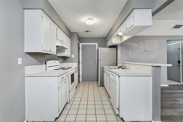 a kitchen with a sink a refrigerator and white cabinets