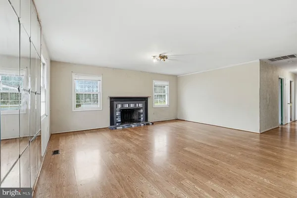 an empty room with wooden floor fireplace and windows