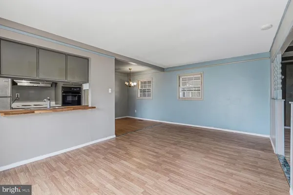 a view of empty room with wooden floor and kitchen