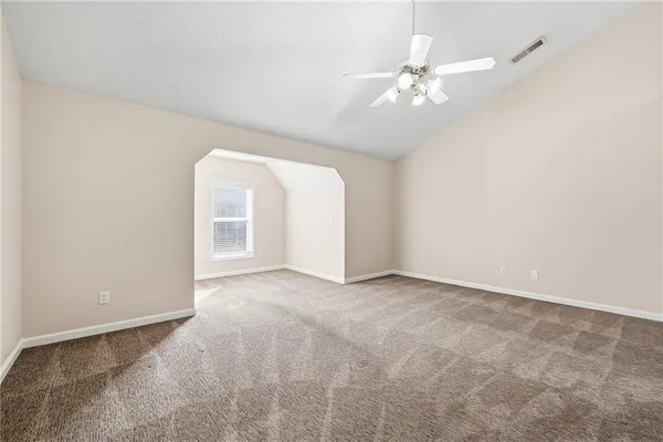 an empty room with a chandelier fan and windows