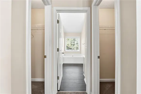 a view of a hallway with wooden floor and a bathroom