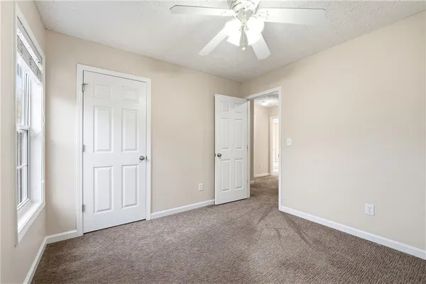 an empty room with a chandelier fan and closet area