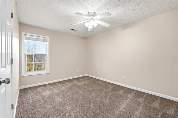 an empty room with windows and chandelier fan
