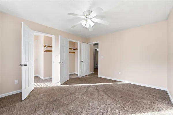 a view of an empty room with chandelier fan
