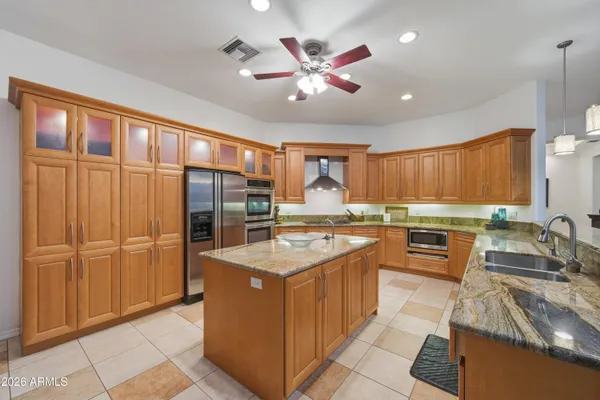 a kitchen with kitchen island granite countertop a sink counter top space appliances and cabinets