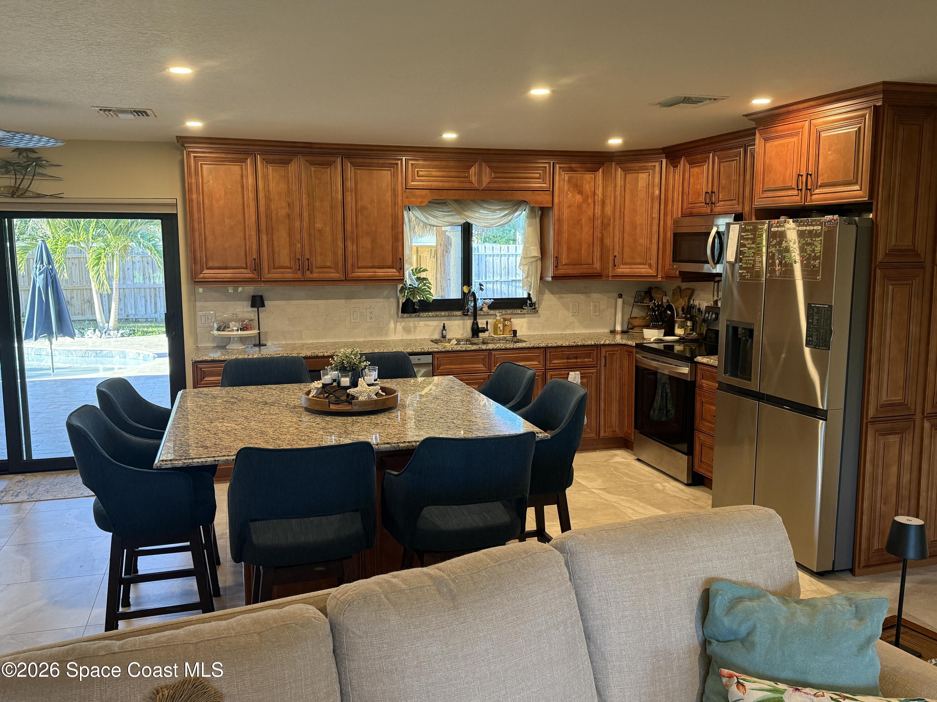 1908 Cedar Lane Melbourne Beach, FL 32951 - Photo 34 of 52 a kitchen with stainless steel appliances granite countertop a refrigerator a sink dishwasher a dining table and chairs with wooden floor