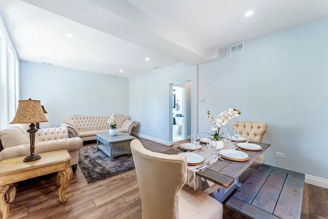 a living room with couches and a dining table with wooden floor