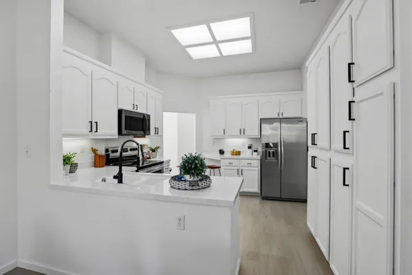 a kitchen with white cabinets and sink