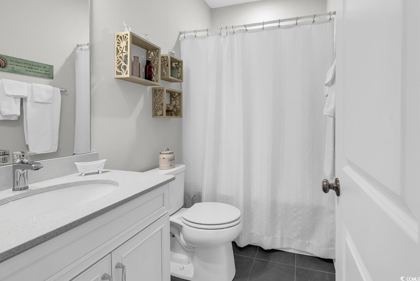6024 Curran Street Murrells Inlet, SC 29576 - Photo 22 of 34 Bathroom featuring a shower with curtain, dark tile patterned flooring, and vanity