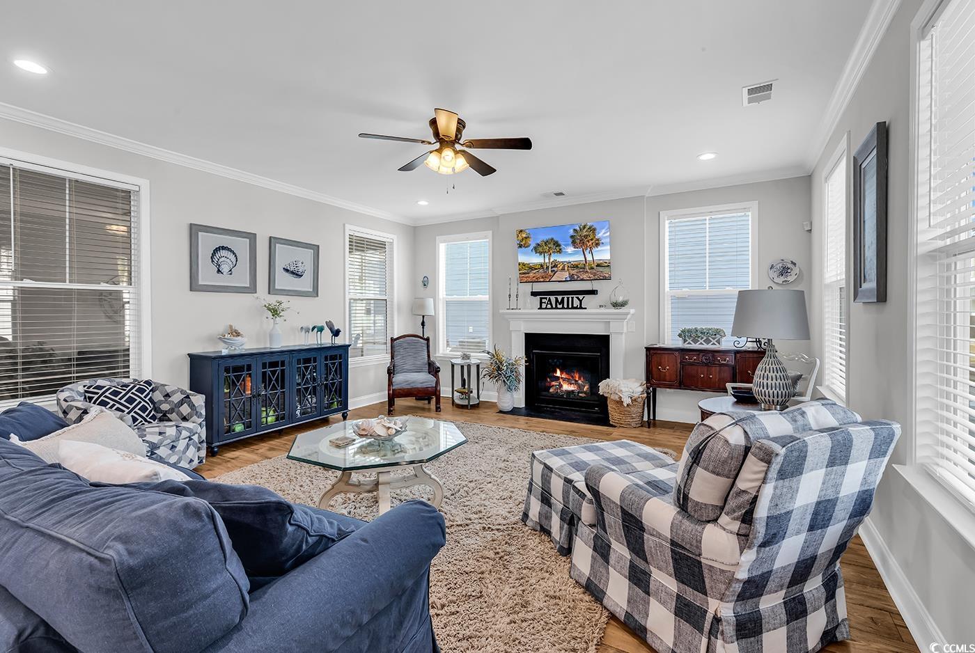 6024 Curran Street Murrells Inlet, SC 29576 - Photo 3 of 34 Living room featuring a fireplace with flush hearth, recessed lighting, wood finished floors, crown molding, and a ceiling fan