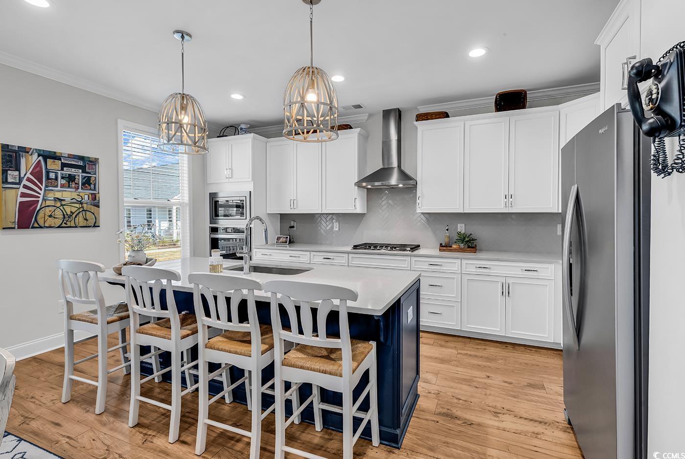 6024 Curran Street Murrells Inlet, SC 29576 - Photo 6 of 34 Kitchen with white cabinets, appliances with stainless steel finishes, pendant lighting, backsplash, and a kitchen bar