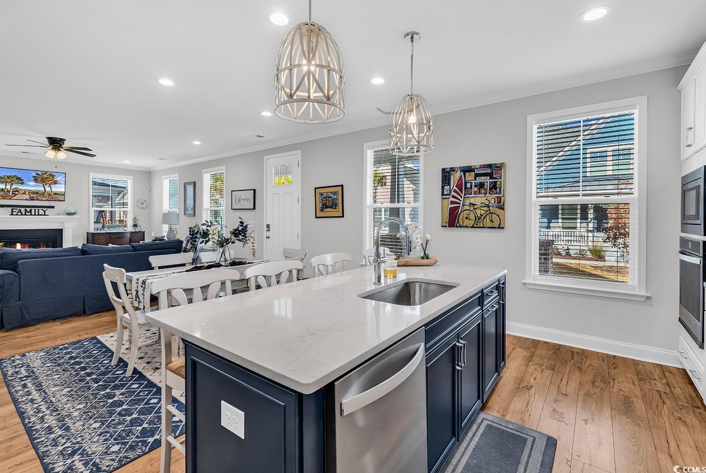 6024 Curran Street Murrells Inlet, SC 29576 - Photo 8 of 34 Kitchen featuring a kitchen bar, light stone counters, a lit fireplace, decorative light fixtures, and ornamental molding