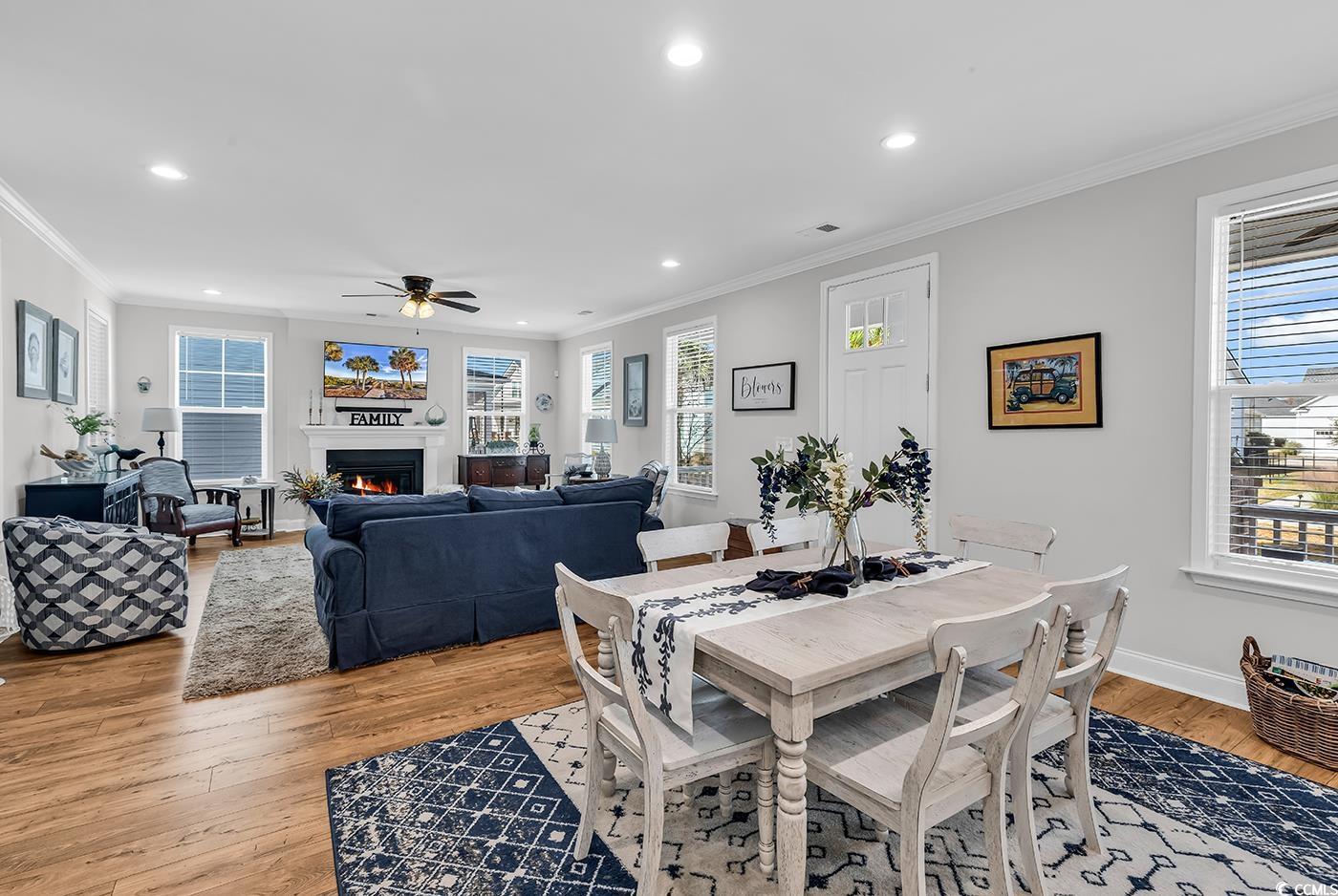 6024 Curran Street Murrells Inlet, SC 29576 - Photo 9 of 34 Dining room featuring a warm lit fireplace, light wood-type flooring, recessed lighting, crown molding, and a ceiling fan