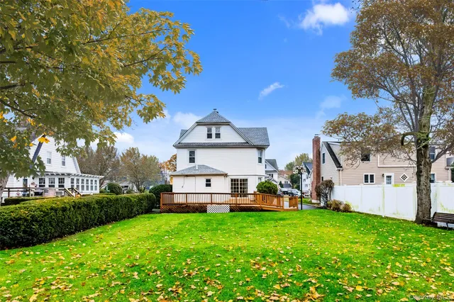 a view of a white house with a big yard and large trees