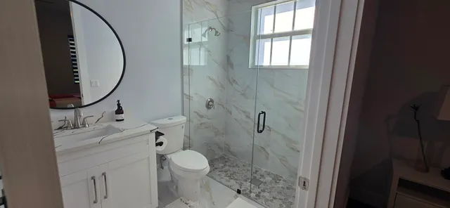 a bathroom with a granite countertop toilet a sink and a mirror