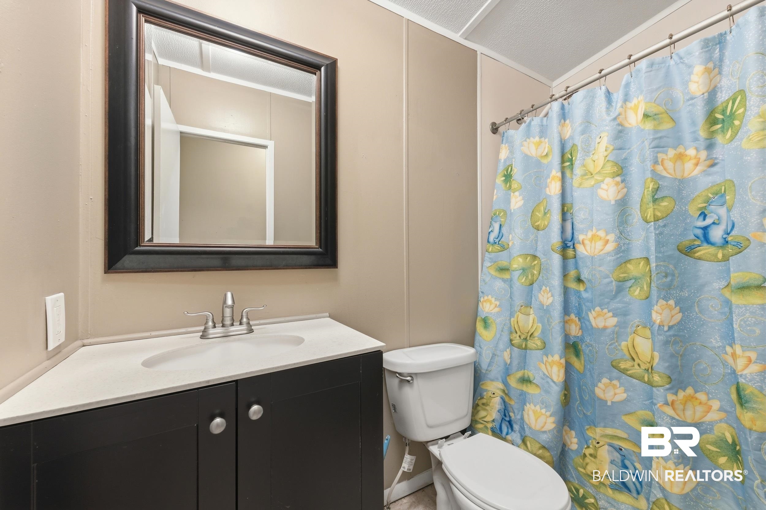 926 Tumbling Lane Atmore, AL 36502 - Photo 37 of 56 Bathroom featuring a corner vanity with an integrated sink, brushed nickel faucet, and a framed wall mirror