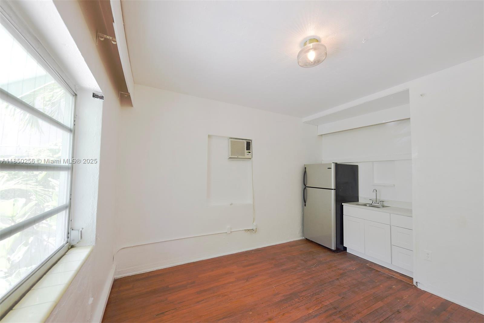 7613 Biscayne Boulevard, Unit 1 Miami, FL 33138 - Photo 5 of 16 a view of empty room with wooden floor and window