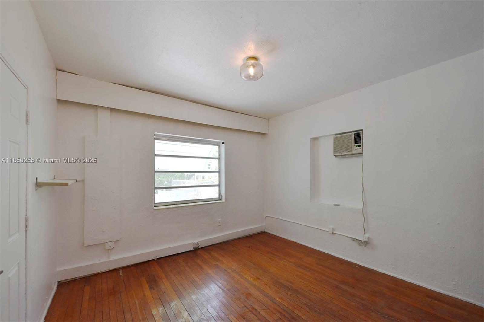 7613 Biscayne Boulevard, Unit 1 Miami, FL 33138 - Photo 6 of 16 an empty room with wooden floor and windows