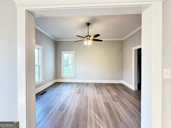 a view of an empty room with wooden floor and a window
