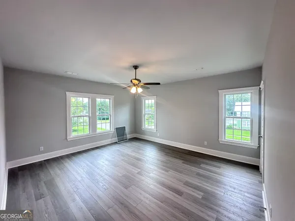 an empty room with wooden floor and windows