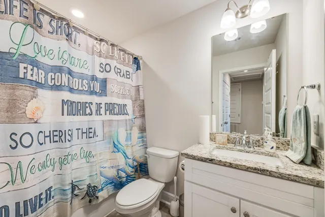 a bathroom with a granite countertop sink mirror vanity and toilet