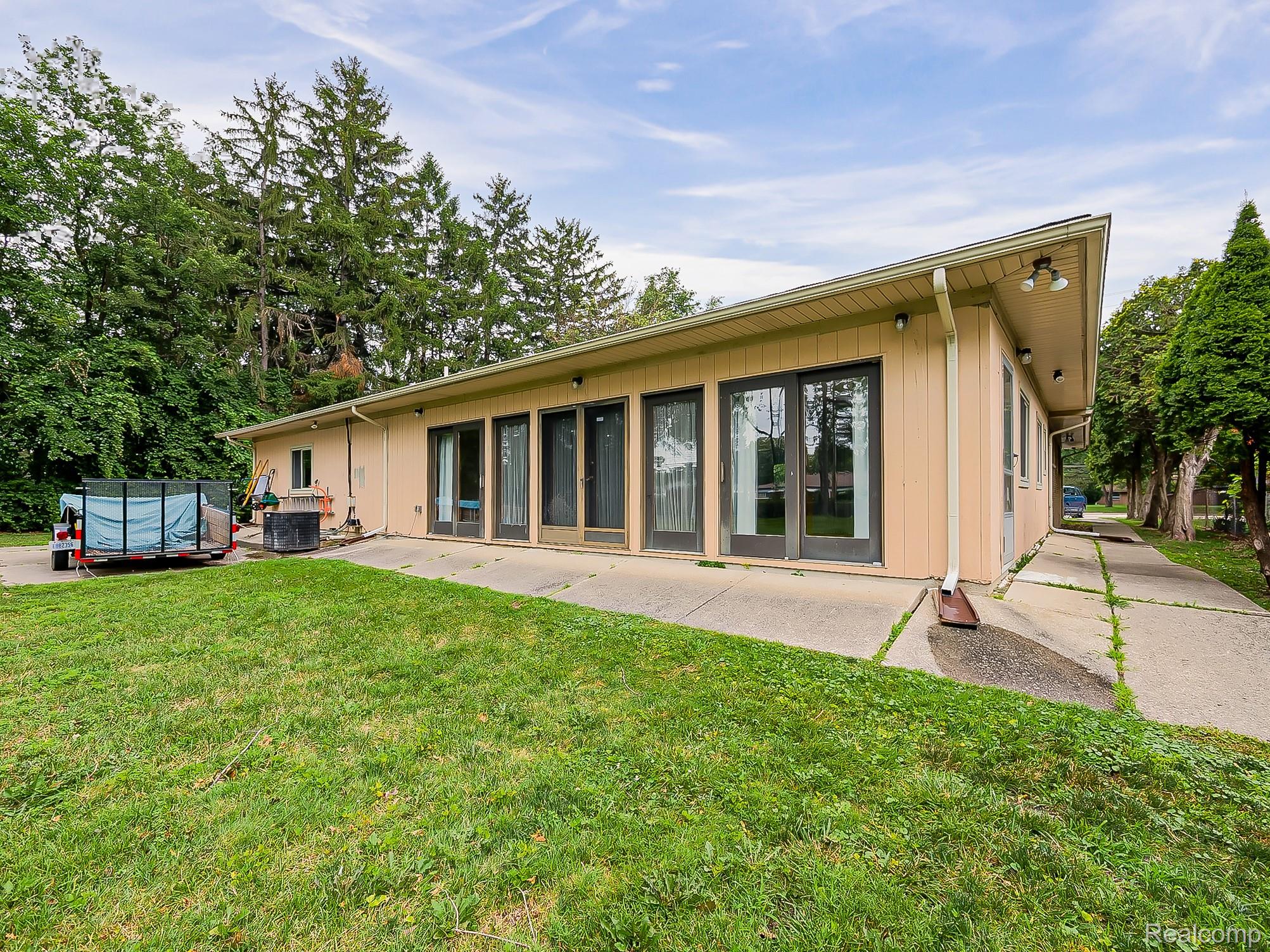 28177 Ryan Road Warren, MI 48092 - Photo 34 of 41 Single-story residence featuring a neutral-toned exterior, a sloped roofline, and multiple glass-paneled doors providing exterior access