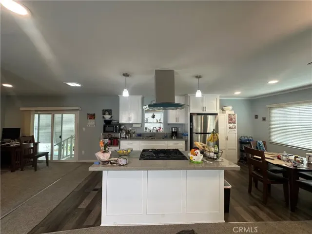 a view of a kitchen with kitchen island stainless steel appliances refrigerator stove dining table and chairs