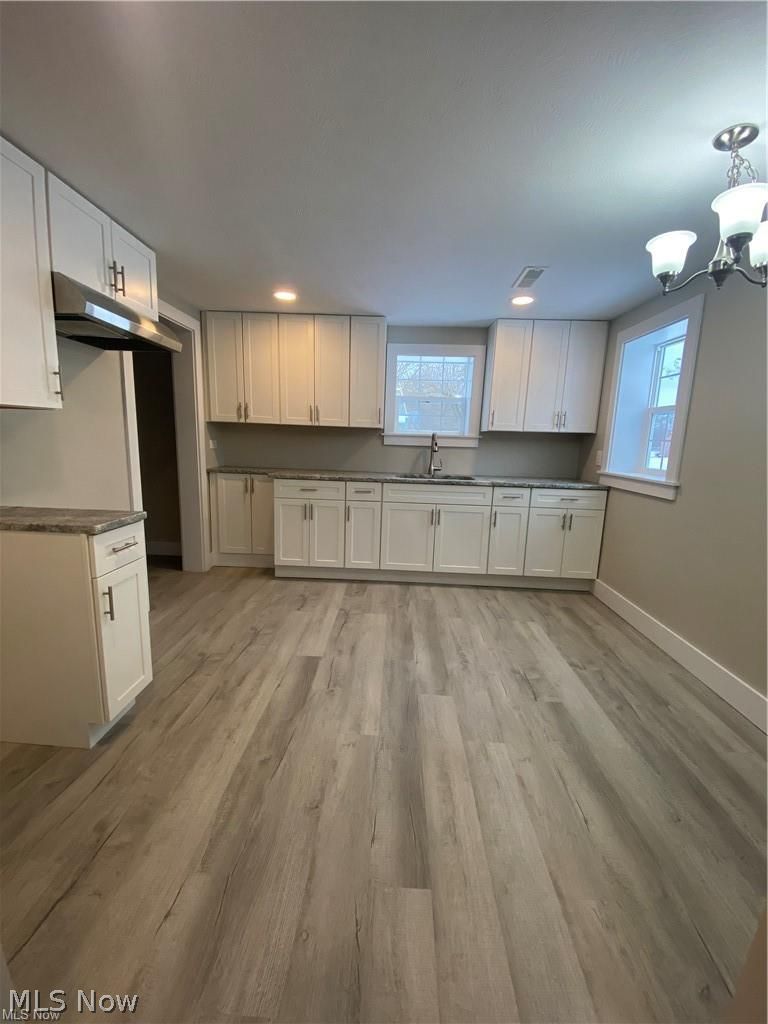 2803 State Road Vermilion, OH 44089 - Photo 11 of 28 Kitchen with brand new white cabinets, light wood-style flooring, Brand new light features, exhaust hood, and gray granite countertops