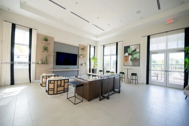 a living room with furniture flat screen tv and large windows