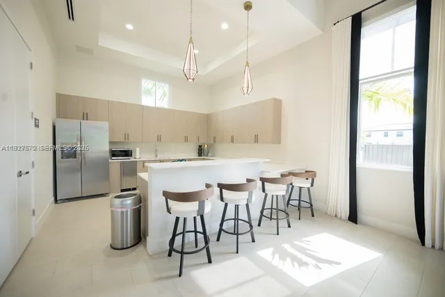 a kitchen with stainless steel appliances kitchen island granite countertop a refrigerator a stove a sink and a dining table with wooden floor